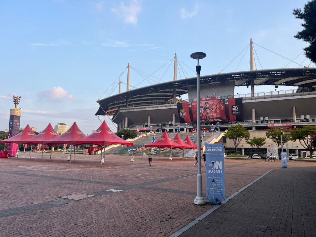 Seoul World Cup Football Stadium, a large stadium with FC Seoul banners, as seen from the outside with a public square in front of it